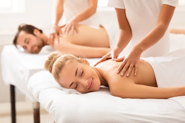 Cônjuges relaxados desfrutando de massagem deitada em camas no Spa Center — Fotografia de Stock