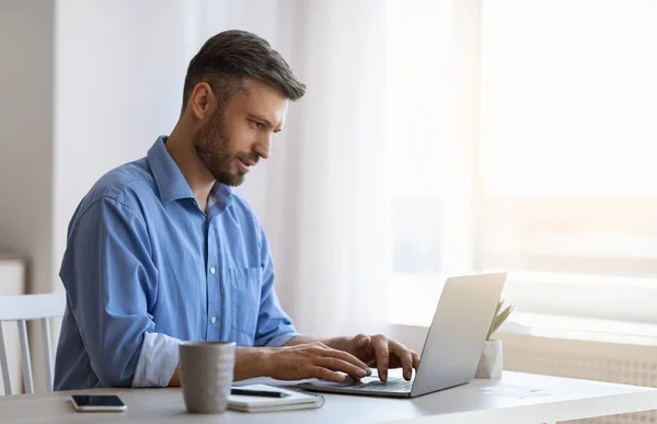 Guapo freelancer masculino trabajando en el ordenador portátil en el escritorio en el hogar Oficina — Foto de Stock