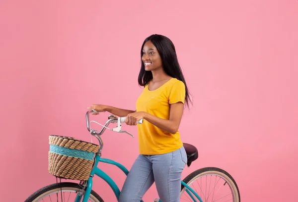 Lovely black woman with vintage bicycle over pink studio background — Stock Photo, Image