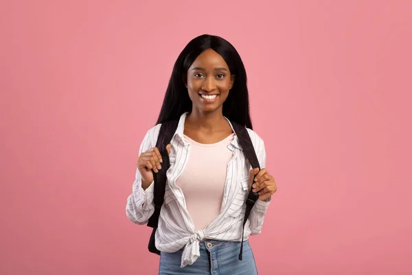 Θετική μαύρη μαθήτρια με σακίδιο κοιτάζοντας την κάμερα και χαμογελώντας σε ροζ φόντο στούντιο — Φωτογραφία Αρχείου