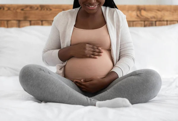 Trzeci trymestr ciąży. Szczęśliwy czarny spodziewa kobieta Obejmuje brzuch na łóżku — Zdjęcie stockowe