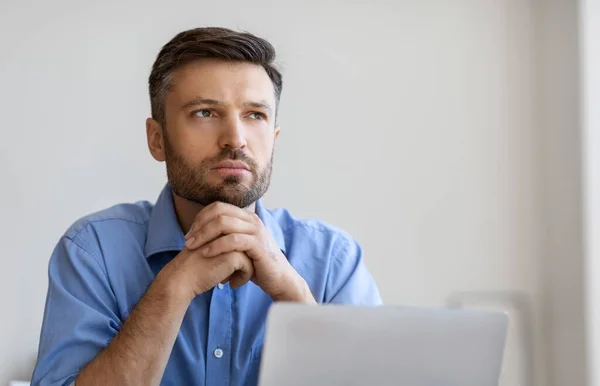 Retrato de Empresário Pensivo sentado no local de trabalho com laptop e olhando para fora — Fotografia de Stock