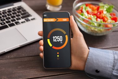 Akıllı yeme ve diyet planlama konsepti. Akıllı telefonu elinde tutan adam, günlük kalorileri saymak için açık uygulamalı, yakın plan.
