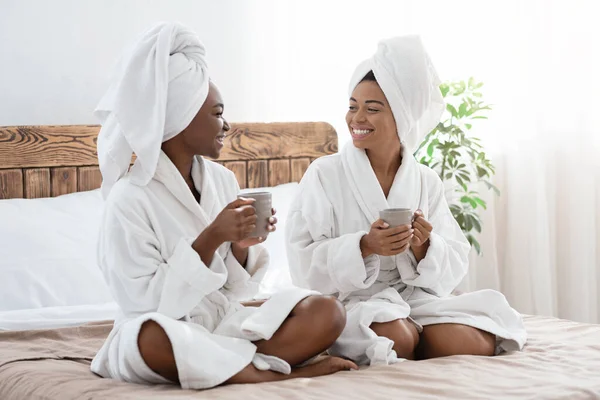 Vrolijke Afrikaanse dames in badjassen die samen tijd doorbrengen. — Stockfoto