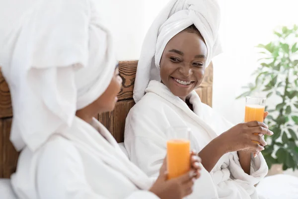 两个快乐的黑人女人在床上喝新鲜果汁 — 图库照片