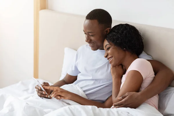 Alegre africano americano pareja viendo fotos juntos en smartphone —  Fotos de Stock