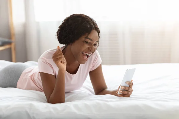 Emocional mujer afroamericana mirando la pantalla del teléfono inteligente — Foto de Stock