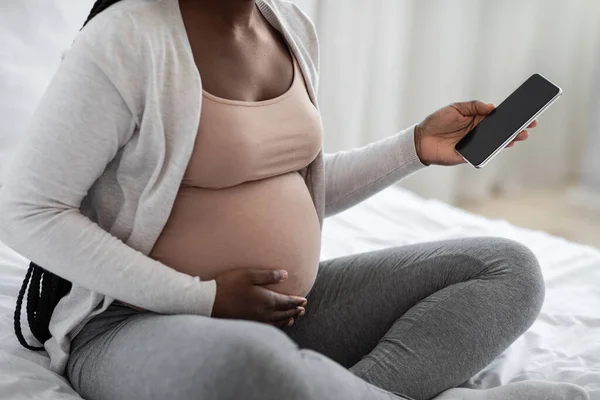 Onherkenbare Afro-Amerikaanse Verwachte Moeder met behulp van Smartphone met zwart scherm thuis — Stockfoto