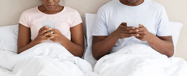 Pareja negra irreconocible usando smartphones en la cama — Foto de Stock