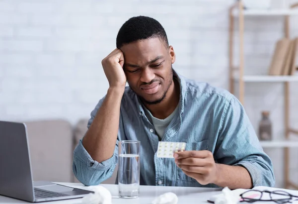 African Man Suffering From Headache Reading Pills Instruction At Workplace — Stock Photo, Image