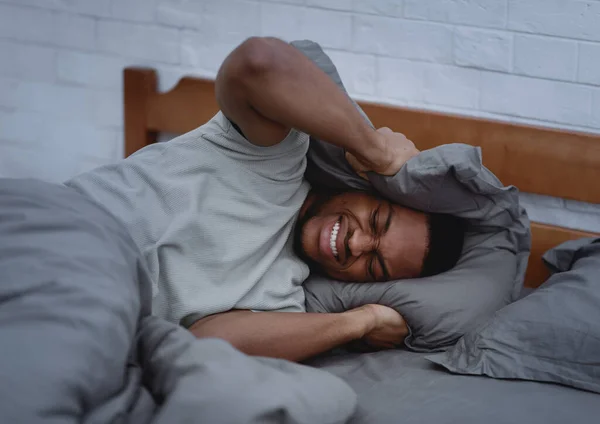 Hombre africano que sufre de dolor de cabeza e insomnio acostado en la cama — Foto de Stock