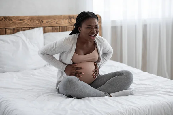 Mulher negra grávida tendo contrações de parto em casa, sofrendo de dor de barriga — Fotografia de Stock