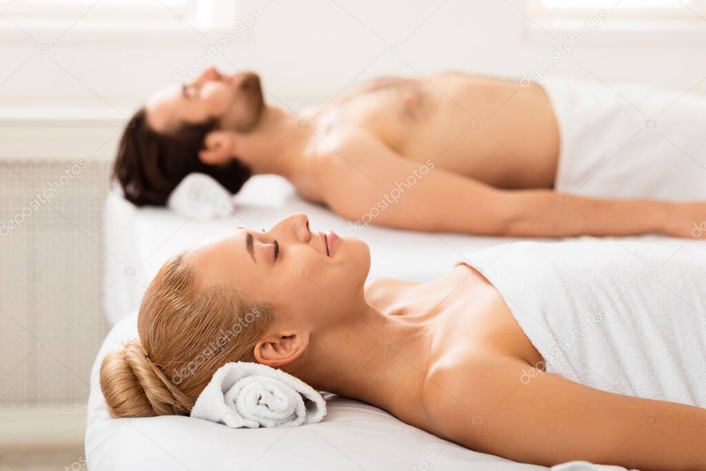 Relaxed Couple After Massage Therapy Lying On Towels Relaxing Indoors