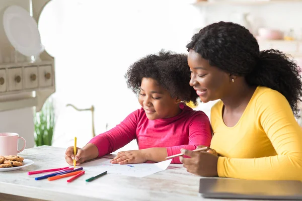 Szczęśliwy czarny matka i słodkie mało córka rysunek razem w kuchnia stół — Zdjęcie stockowe