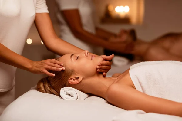 Casal desfrutando de massagem facial no spa, deitado com os olhos fechados — Fotografia de Stock