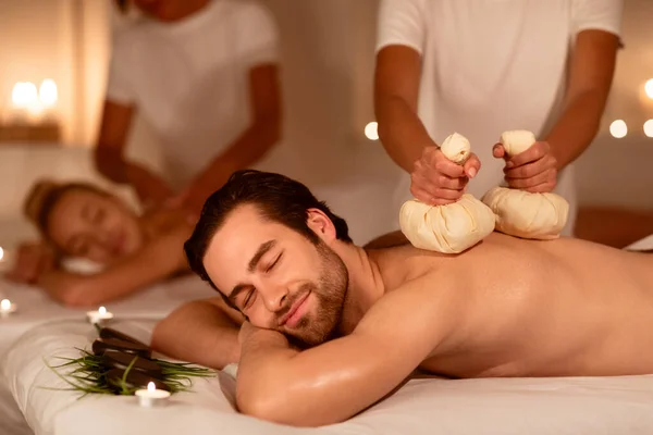 Супруги наслаждаются травяным массажем и ароматерапией, расслабляясь в спа — стоковое фото