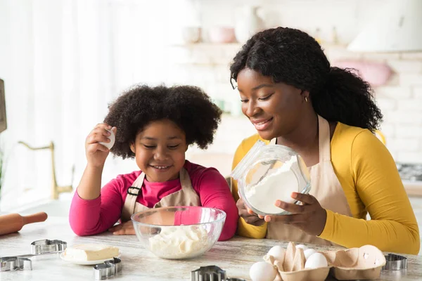 Wesoły czarny matka i mała córka przygotowuje ciasto w kuchni razem — Zdjęcie stockowe