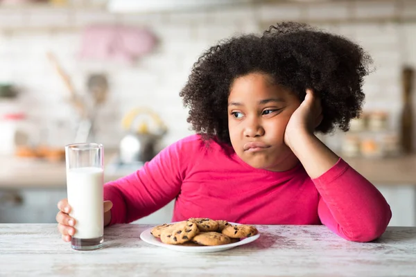 우유와 쿠키와 함께 식탁에 앉아 있는 귀여운 흑인 소녀 — 스톡 사진
