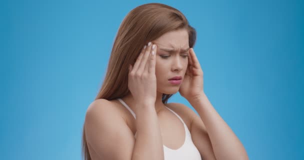 Acute hoofdpijn. tempels, lijden aan migraine aanval, blauwe studio achtergrond — Stockvideo