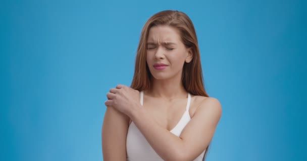 Trauma olahraga. Studio ditembak wanita muda menderita sakit bahu, latar belakang biru — Stok Video