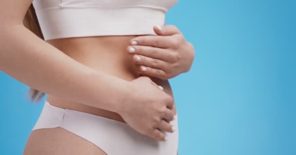 Боль во время менструаций. Крупный план молодых неузнаваемых женщин, трогающих ее желудок, чувствующих боль и судороги — стоковое видео