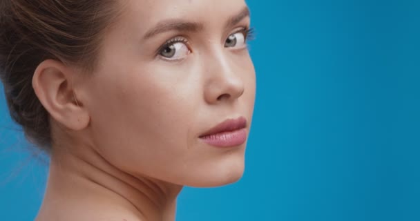 Retrato de belleza de hermosa dama caucásica posando en la cámara, girando la cara, fondo de estudio azul — Vídeo de stock