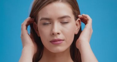 Doğal güzellik. Genç ve güzel bir bayanın stüdyo portresi, güzel saçlar, doğrudan kameraya bakmak, mavi arka plan.