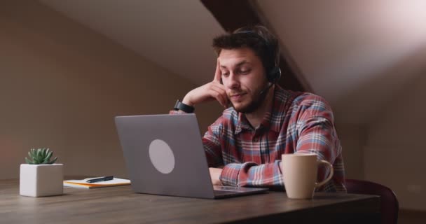 Pemuda yang tidak tertarik mendengarkan ceramah atau webinar di rumah, merasa bosan, melihat laptop dengan kebosanan — Stok Video