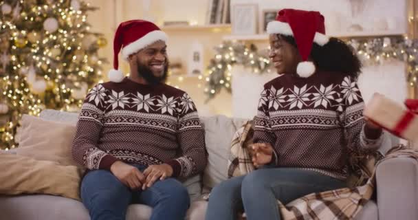 Šťastná africká Američanka blahopřeje svému příteli, dává mu dárek box, Vánoce oslavy společně doma — Stock video