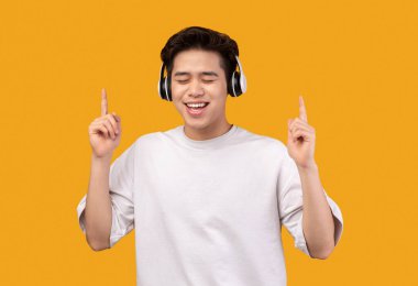 Gülümseyen Asyalı adam kulaklıklı müzikten hoşlanıyor.