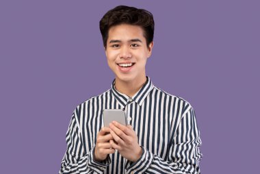 Stüdyoda cep telefonu kullanan gülümseyen Asyalı genç adam.