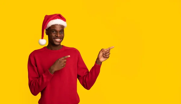 Oferta de Navidad. alegre negro hombre en santa sombrero señalando en copia espacio — Foto de Stock