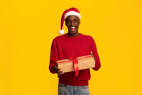 Sorpresa de Navidad. alegre africano chico en santa sombrero posando con regalo caja — Foto de Stock