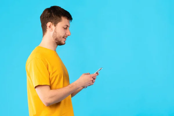 Portrait of young guy using mobile phone, side view — Stok Foto