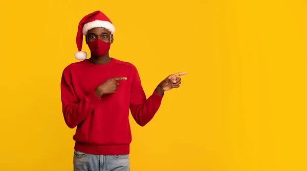 Africano chico en protección cara máscara y Navidad santa sombrero señalando fuera — Foto de Stock