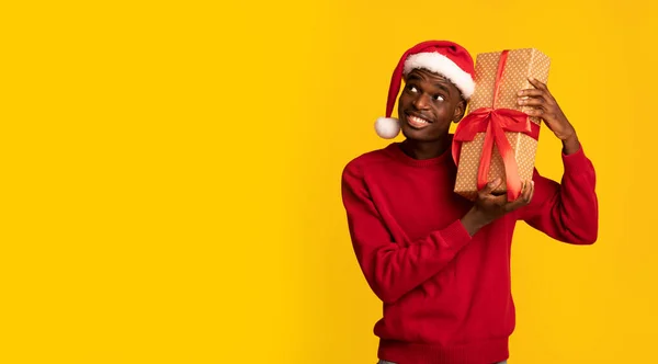 Emocionado hombre negro en Santa Sombrero Shaking envuelto caja de regalo, recibir regalos de Navidad — Foto de Stock
