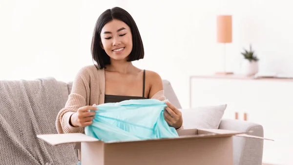 Gelukkig aziatische dame verpakking kleding thuis — Stockfoto