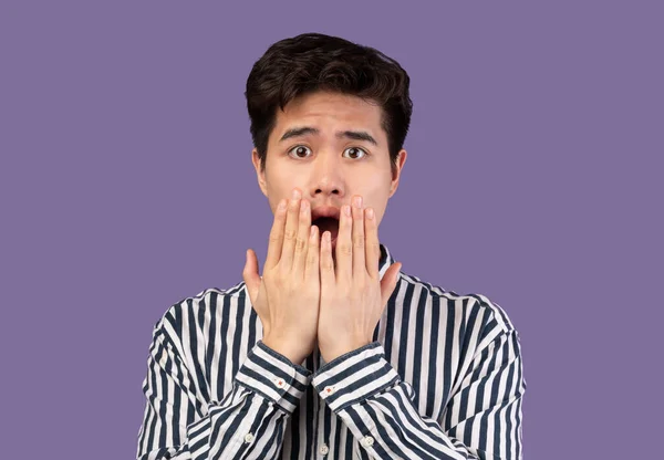 Наляканий азіатський чоловік посміхається, шокований в фіолетовій студії — стокове фото