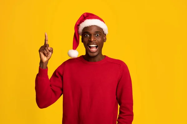 Emocionado hombre negro en Santa Sombrero señalando dedo hacia arriba, teniendo idea de Navidad — Foto de Stock