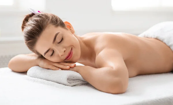 Radosna pani leżąca na stole do masażu w salonie spa — Zdjęcie stockowe