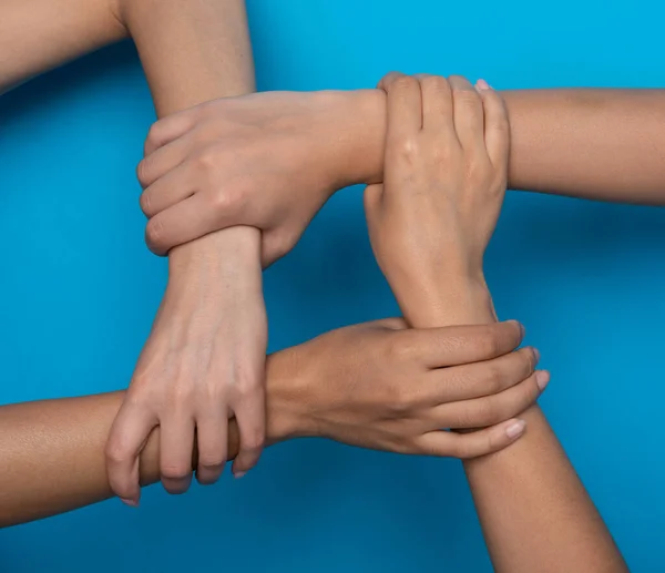 Αγνώριστες γυναίκες κρατώντας τα χέρια Συμβολίζει Togetherness, μπλε φόντο, περικοπή — Φωτογραφία Αρχείου