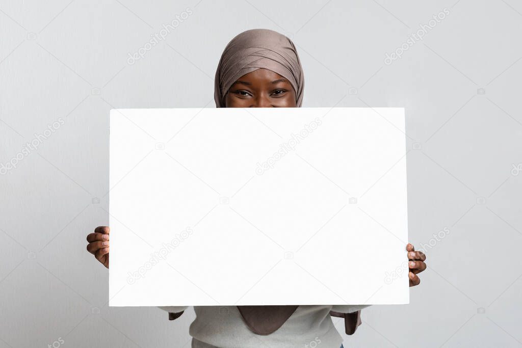 Copy Space For Ad. Black Woman In Hijab Hiding Behind White Placard