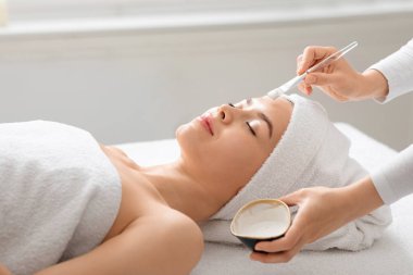 Uyuyan bayanın yüzüne kilden maske takan tanınmamış spa görevlisi