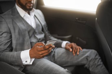 Arabada cep telefonu kullanan siyahi bir işadamı.