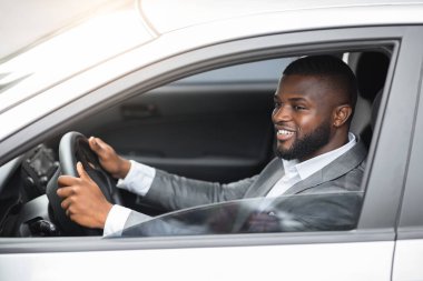 Takım elbiseli Afrikalı Amerikalı genç adam araba kullanıyor.