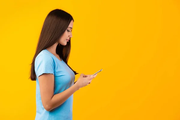 Porträt einer jungen Frau, die ihr Handy benutzt, Seitenansicht — Stockfoto