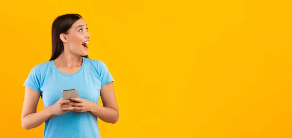 Verrassende vrouw met mobiele telefoon in de studio, panorama — Stockfoto