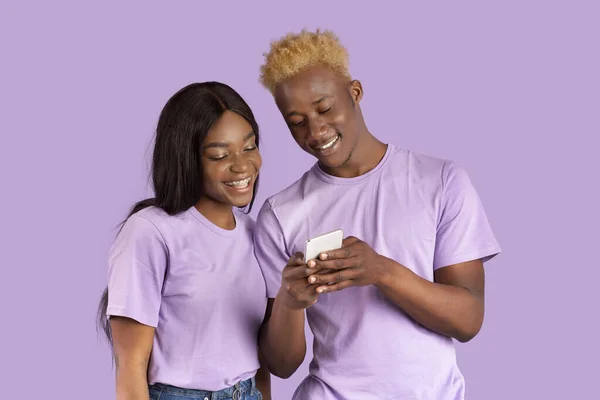 幸せな黒女性とともに携帯電話で一緒に上の紫のスタジオの背景 — ストック写真
