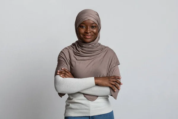 Αυτοπεποίθηση μαύρη μουσουλμάνα γυναίκα θέτει με διπλωμένα χέρια πάνω από το φως φόντο — Φωτογραφία Αρχείου