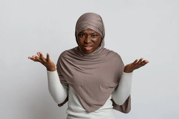 Niezadowolony czarny muzułmanin kobieta w hidżab rozprzestrzenianie ręce podczas narzekania przed kamerą — Zdjęcie stockowe